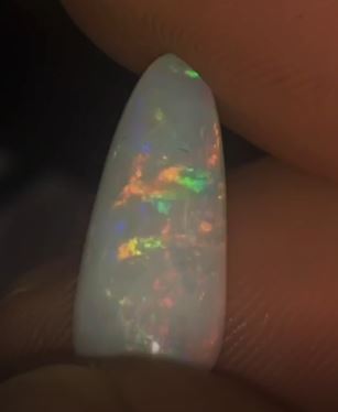 Bright flashes of pink, orange and green show in this teardrop shaped opal gem